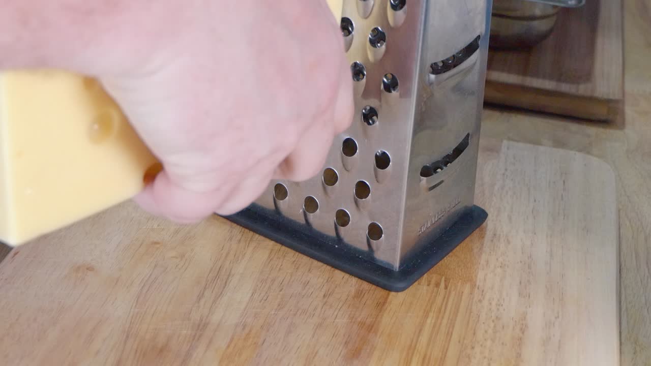 plano medio de rallar queso emmental con un rallador de queso de caja