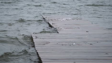 close up view of lake water playfully jumping out through the wooden deck