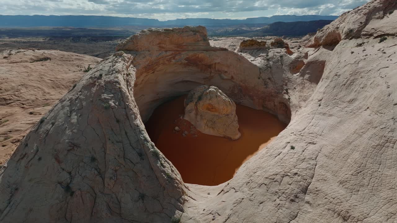 Ampia ripresa drone del bacino roccioso Cosmic Ashtray con sabbia arancione circondato dal deserto dello Utah.
