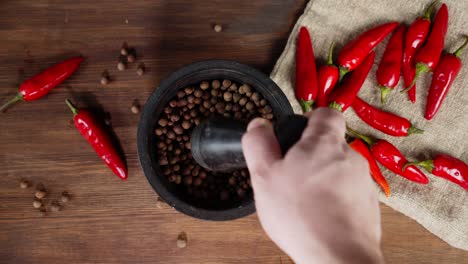 the man's hand stir of black pepper in a mortar.