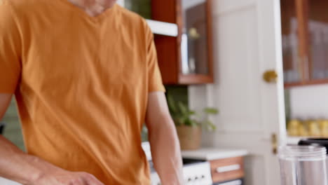 Focused-biracial-man-chopping-fruit,-preparing-healthy-smoothie-in-kitchen,-copy-space,-slow-motion