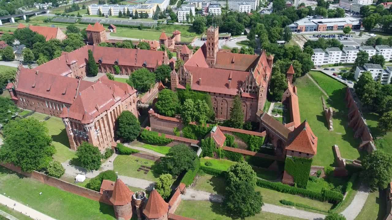 Detailed drone shot over Malbork Castle highlighting towers, Gothic halls, and fortification layers. Malbork, Poland