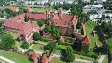 detailed drone shot over malbork castle highlighting towers, gothic halls, and fortification layers. malbork, poland