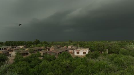 Aerial-drone-tilt-down-shot-over-village-houses-in-Mirpurkhas,-Sindh,-Pakistan-with-dark-rain-clouds-during-evening-time