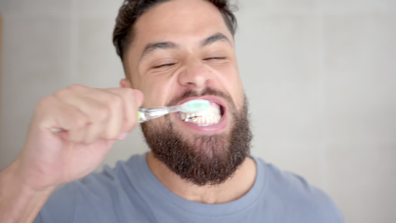 Brushing teeth, bearded man smiling and maintaining oral hygiene at home