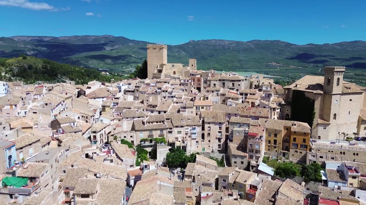 Vista aerea con drone della storica città di Calasparra nel sud della Spagna, con case del centro storico, castello medievale, paesaggio montano, architettura tradizionale, destinazione di viaggio e un panoramico panorama urbano.