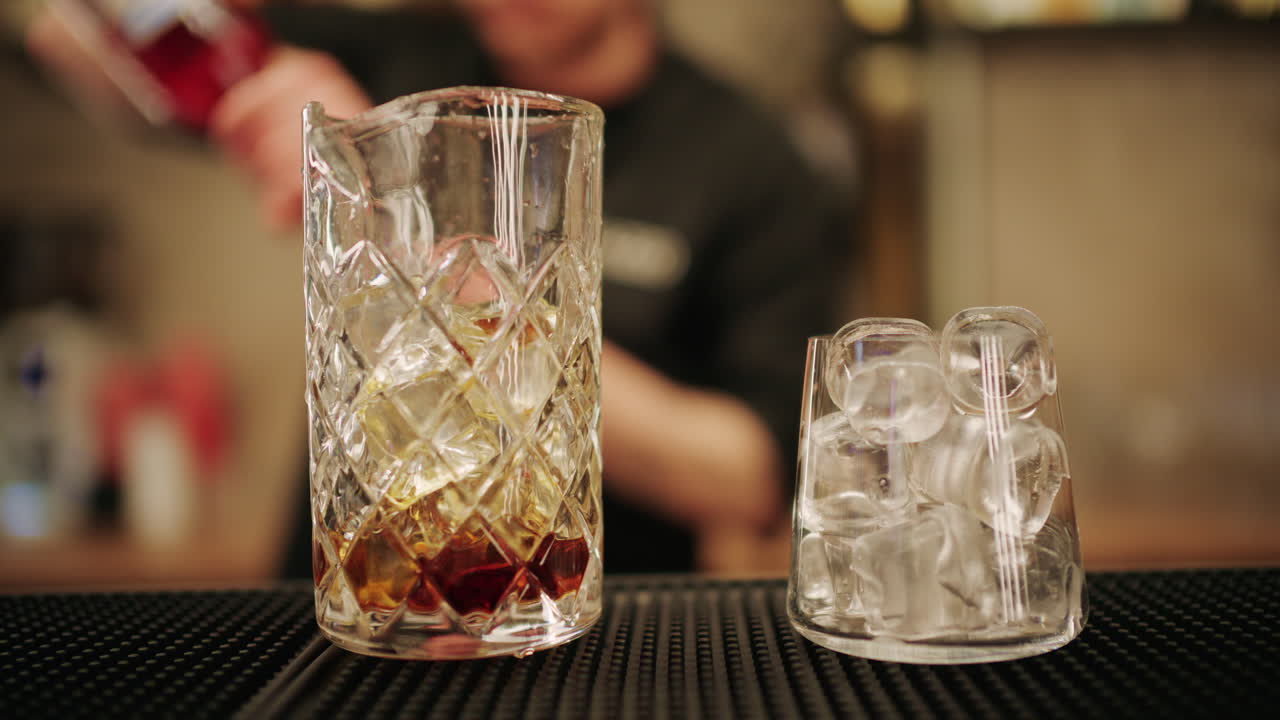 Barman professionista che versa liquore in un mixing glass con cubetti di ghiaccio