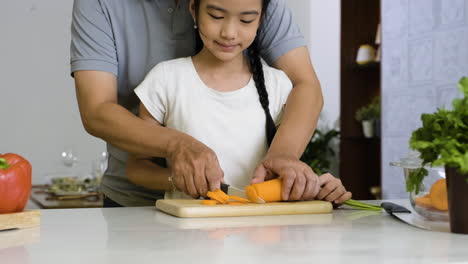 Father-and-daughter-cutting-carrot.