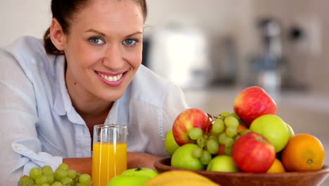 bonita morena sonriendo a la cámara detrás de la fruta