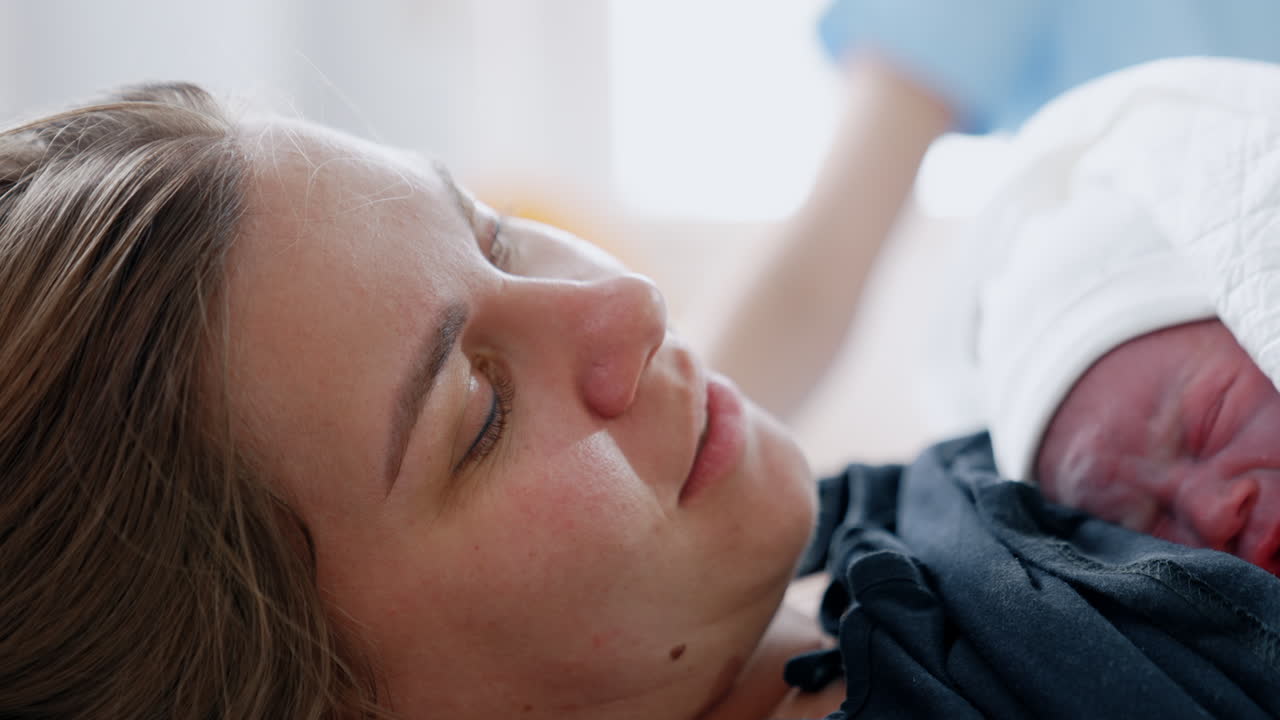 Caucasian woman with a tiny newborn on the chest. Little child is crying on mom's chest. Close up.