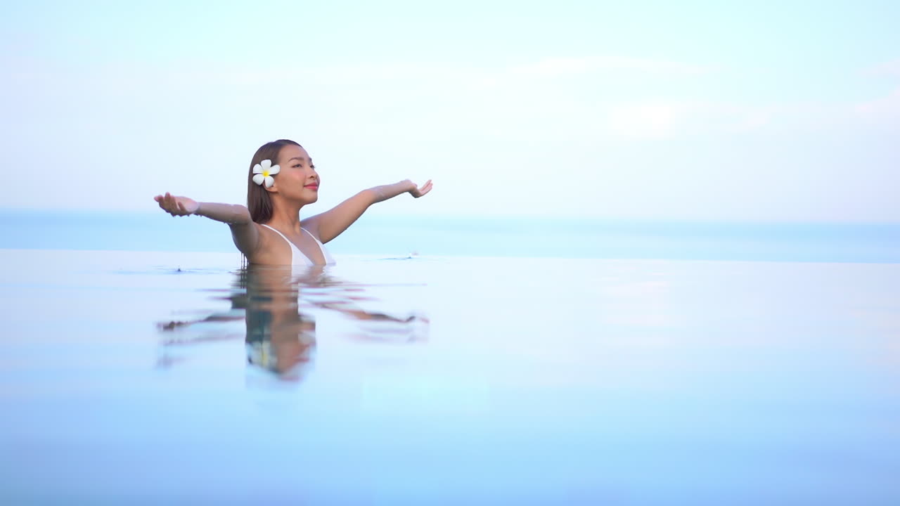 летняя девушка отдыхает в бассейне, раскинув руки, мягкий фокус