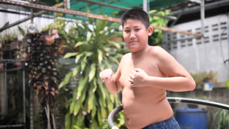 fat boy playing hula hoop at backyard, slow motion with belly moving.