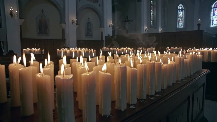 When shot begins camera panning across votive candles on table in church revealing smoke and arches