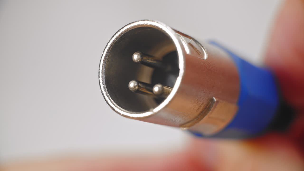 holding blue and silver, audio, XLR sound cable plug in fingers