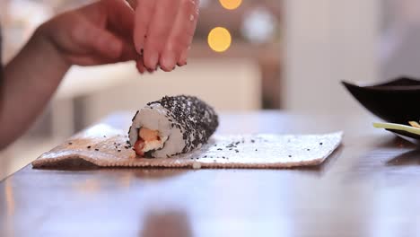 making sushi at home kitchen. woman hands rolling homemade sushi.