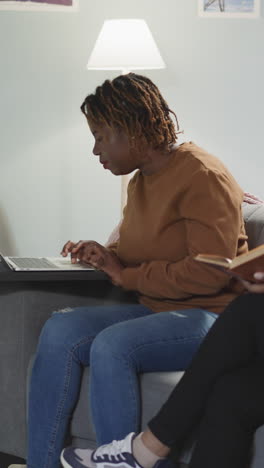 multinational lady students look for information using books and internet. indian woman reads while african american girl friend examines websites on laptop