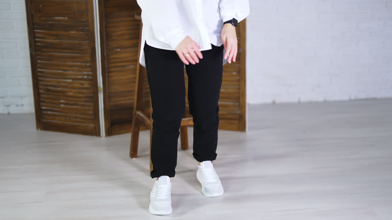 Model jumping high to show white spot shoes. Demonstrating comfortable footwear for everyday activity. Folding screen and tabouret at backdrop.