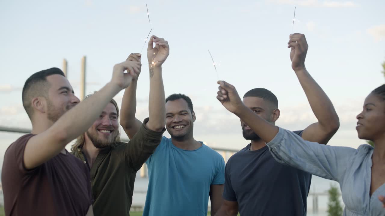 jóvenes sonrientes bailando con luces bengalíes