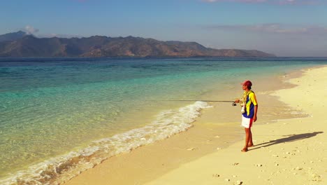 joven pescador tratando de pescar lanzando caña de pescar en aguas tranquilas y claras del mar azul en la hora dorada del atardecer en vietnam