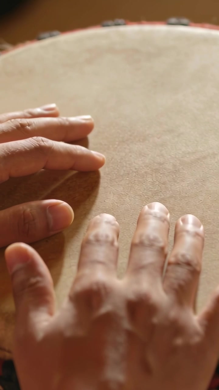 Video verticale: Mani del musicista che sollevano i palmi, battono e smorzano un tamburo a mano a casa per variare i toni, in una band.