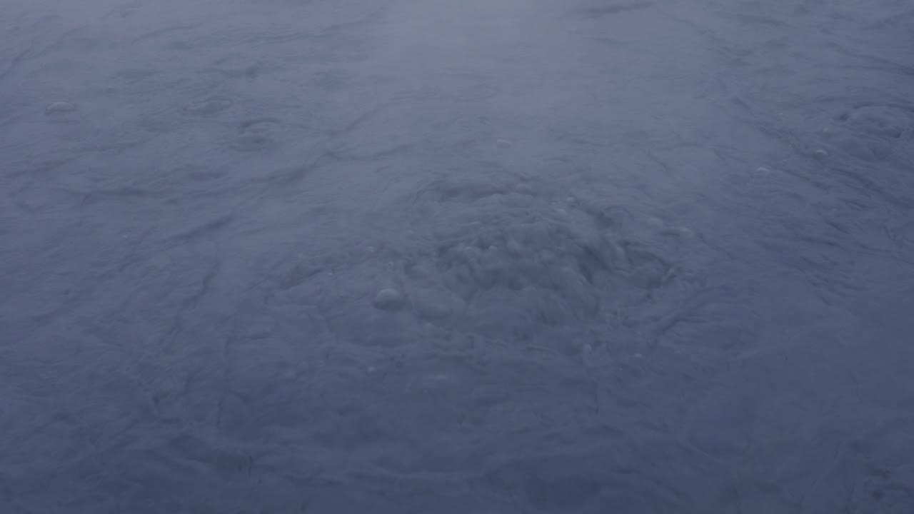 Pozo de lodo hirviendo azul oscuro con vapor elevándose, Islandia.