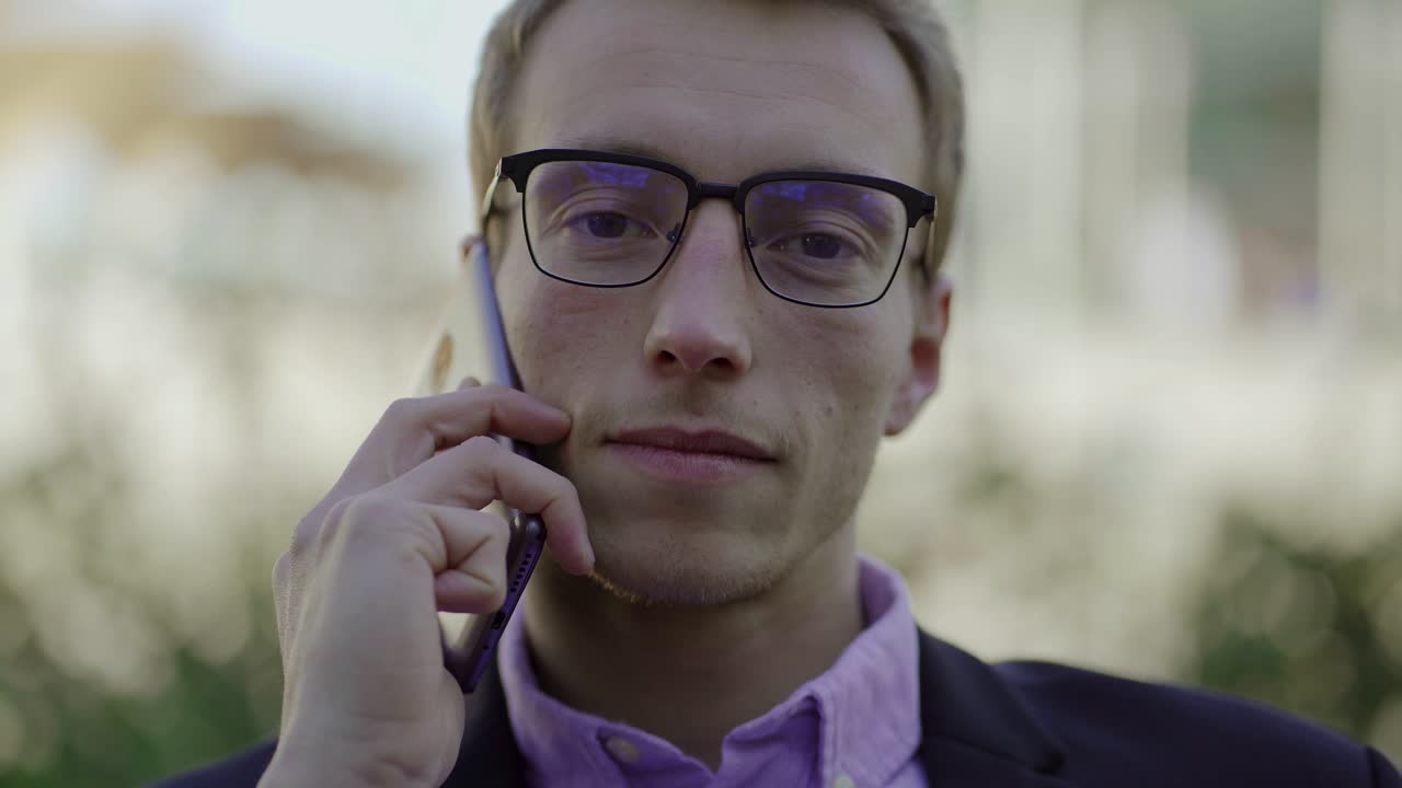 Handsome businessman in eyeglasses talking on phone and laughing