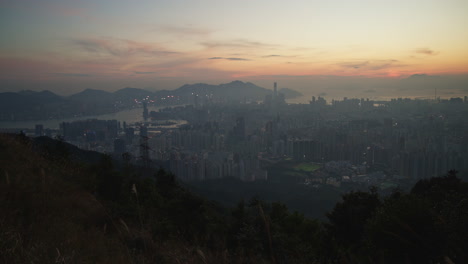 hillside peak view over hong kong kowloon city skyline with highrise buildings during sunset