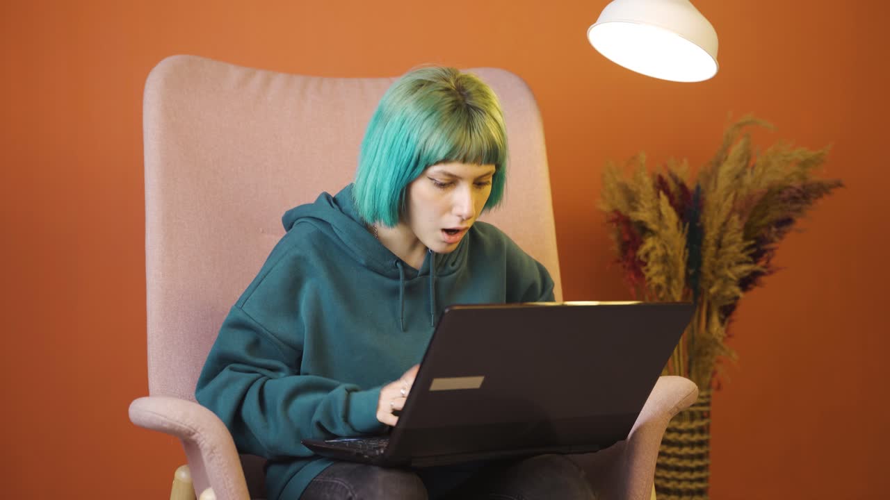 mujer joven mirando la computadora portátil con asombro.