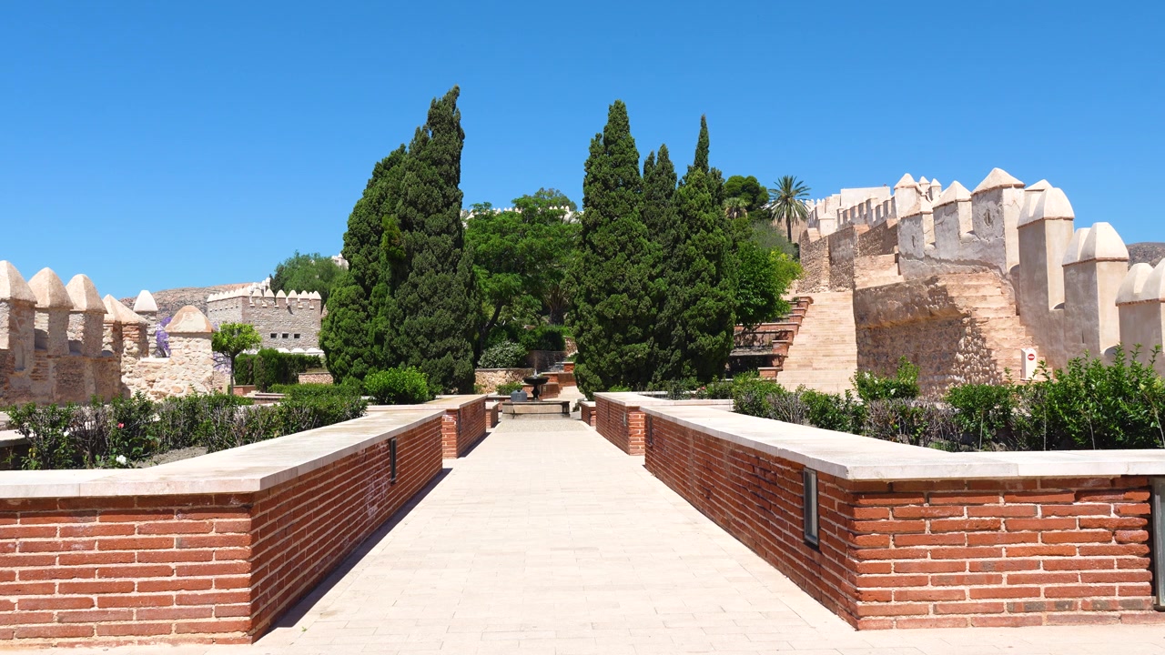 Symmetrisk havegang fører gennem Alcazaba af Almeria-fæstningen med cypresser og historiske forsvarsmure i Andalusien, Spanien
