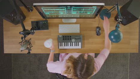 overhead view of female musician at workstation with keyboard and microphone in studio