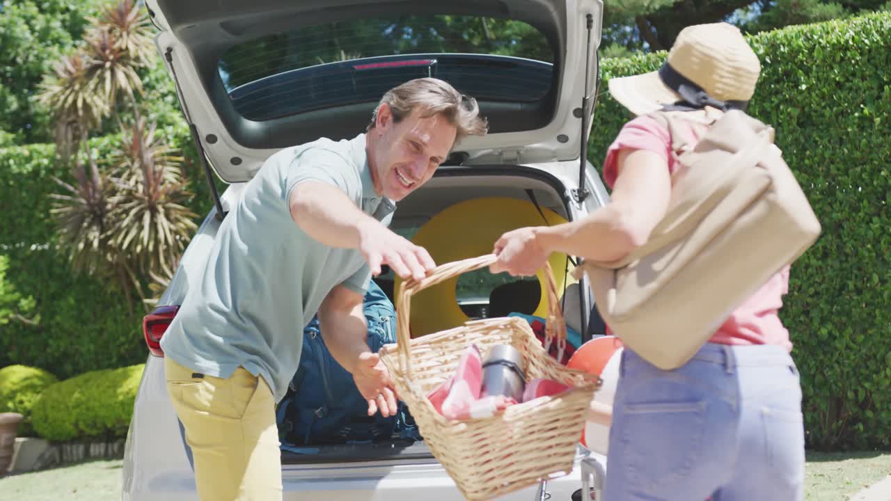 feliz pareja caucásica con hijo empacando el coche y preparándose para las vacaciones