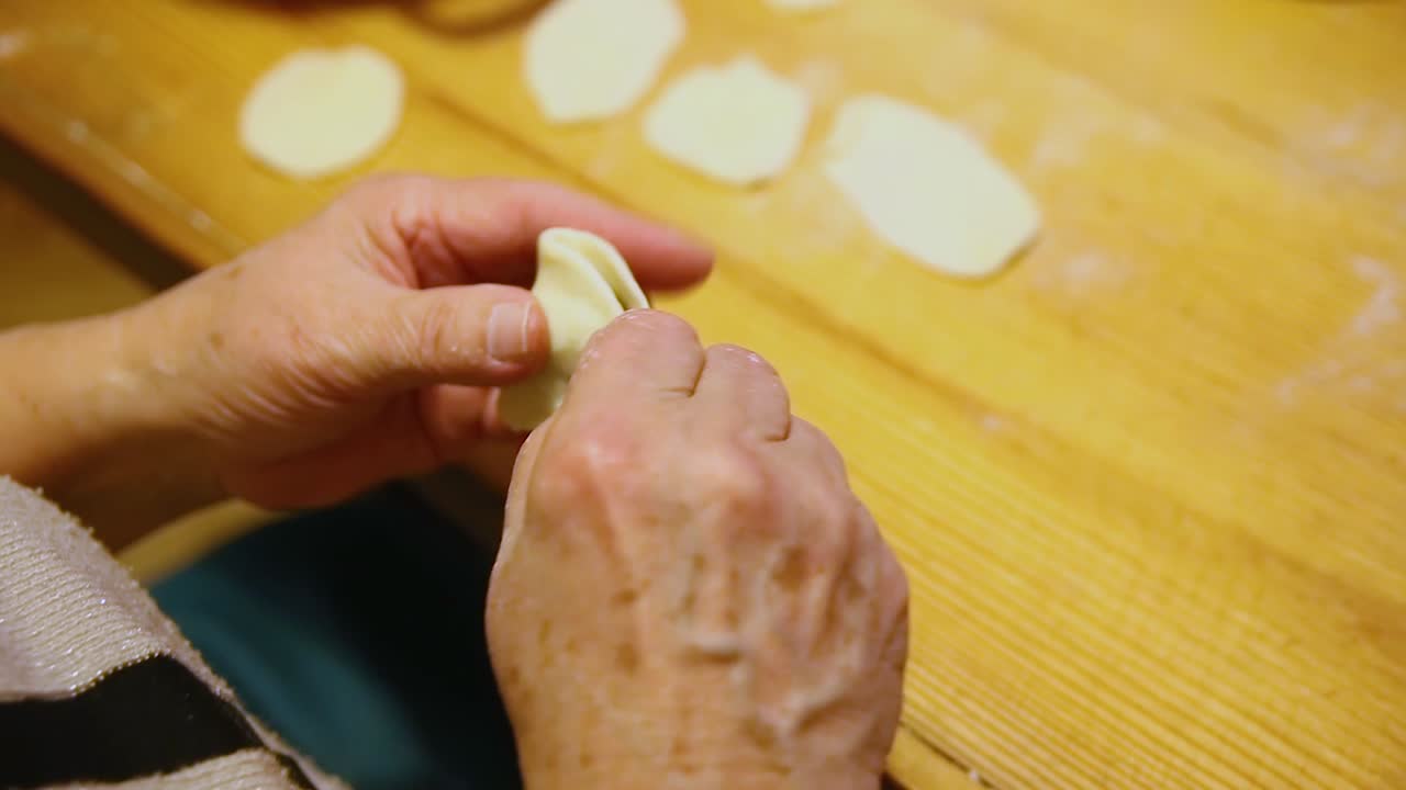 primer plano en manos de una anciana llenando dumpling con ciruela pasa