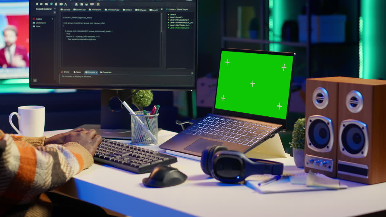 Software developer working on a laptop with a green screen in a home office