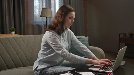 woman working from home on couch with laptop and phone