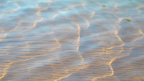 textura ondulada de la superficie del agua sobre arena blanca pura con refracción de la luz solar