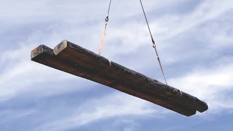 vigas de madera pesadas siendo levantadas por una grúa