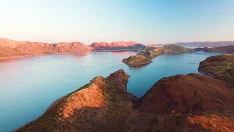 aerial tracking shot of spectacular lake and arid mountains at dusk