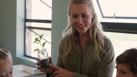 Female-teacher-holding-plant-in-the-class