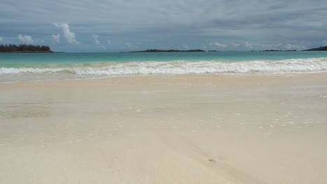 a beautiful tropical seascape of bermuda's clear blue water, and calm waves crashing on to the sand