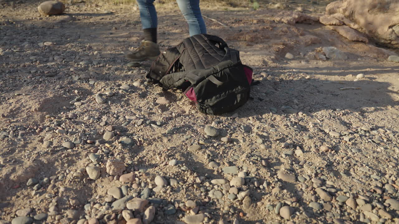 여성 배 ⁇  여행자 는 사막 산책 에서 바위 지대 에 장비 를 남긴다
