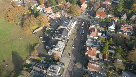 aerial of bus driving over street in a small town in autum