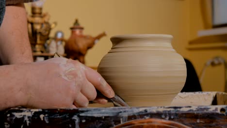 professional potter shaping pot with special tool in pottery workshop