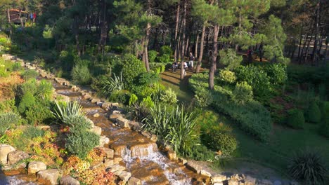 a scenic park with a flowing stream and people enjoying the day