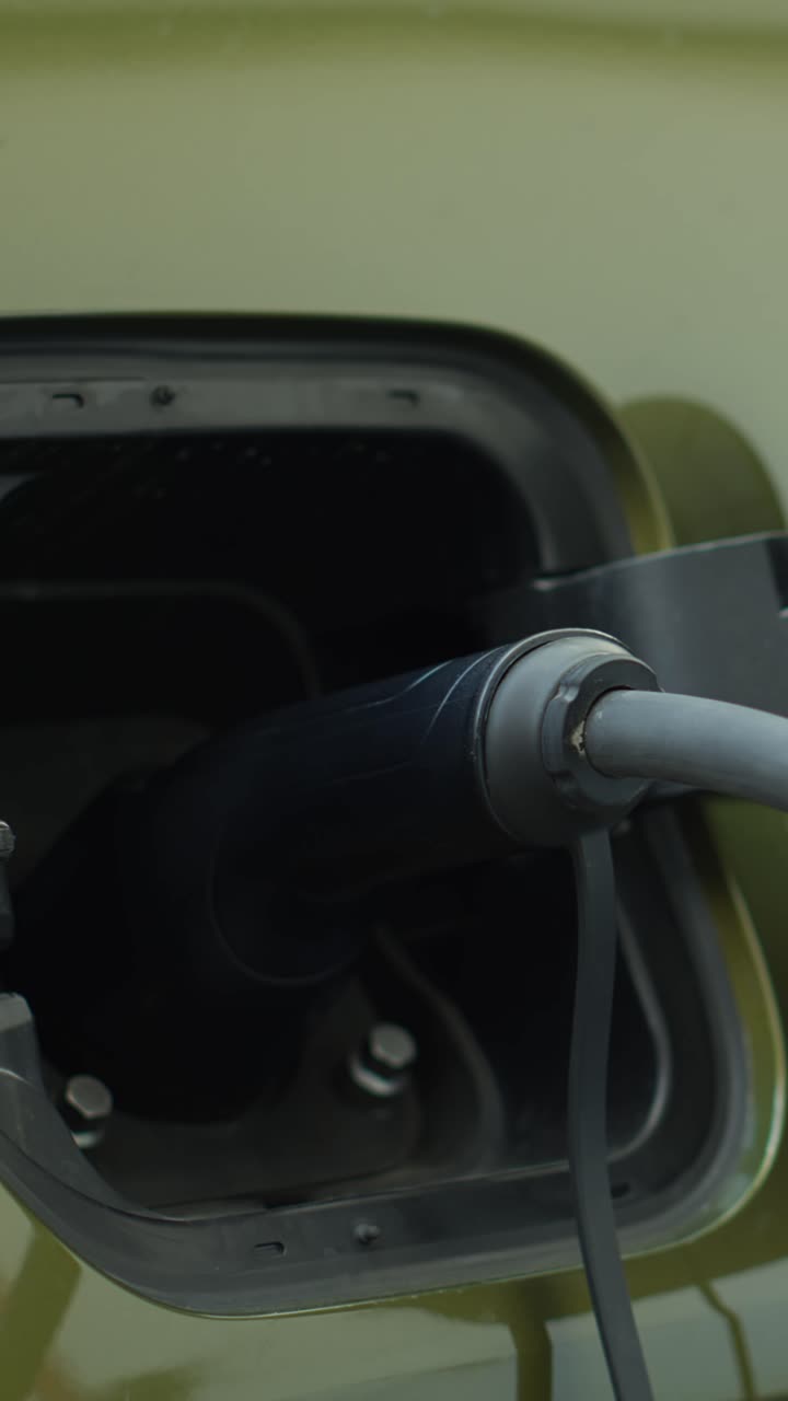 Vertical video Closeup of zero emission EV vehicle connected to charging dock