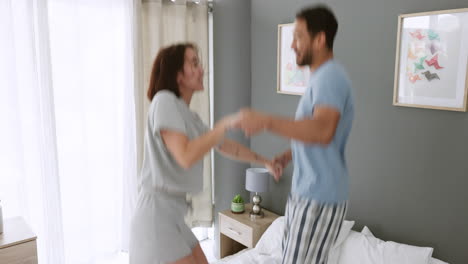 Couple-jumping-on-a-bed,-holding-hands