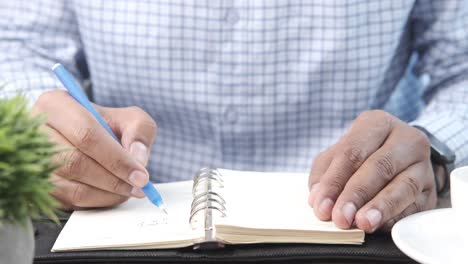 person writing in a notebook at a table