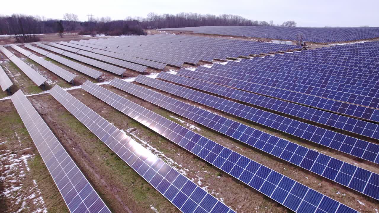 Forward drone shot over panels at huge solar power farm in Michigan