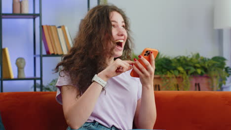 mujer joven feliz en casa usar teléfono inteligente escribir navegación wow sí descubrió gran gran victoria celebrar