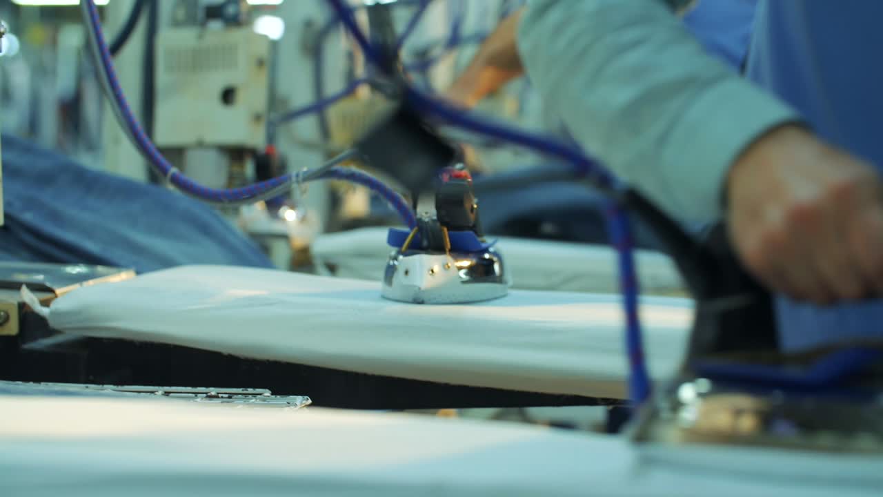In the jeans production factory, workers iron the jeans