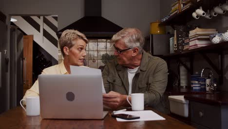 una pareja de ancianos caucásicos clasificando las finanzas con una computadora portátil.